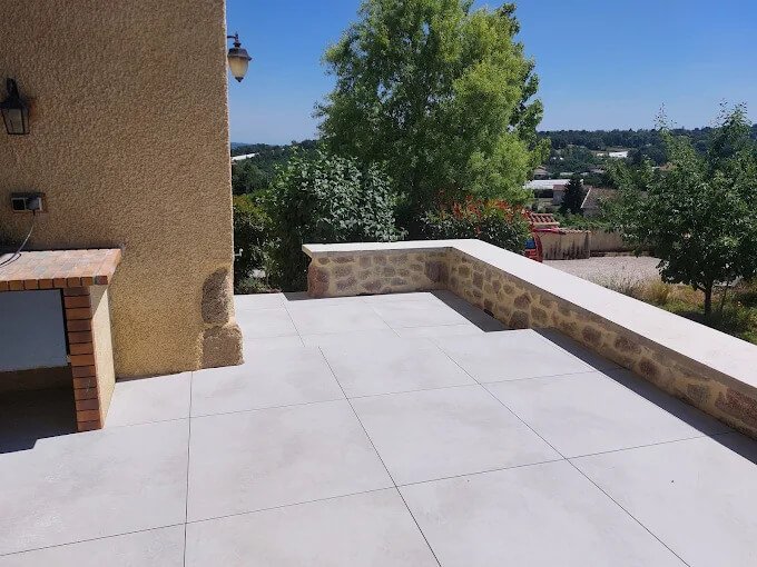 Terrasse en carrelage gris grand format avec découpe sur mesure.